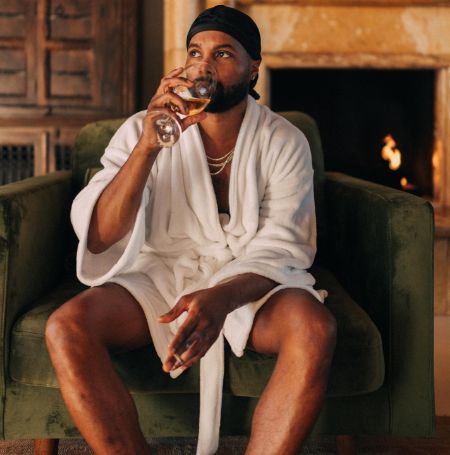 Steelo Brim posed with a glass of wine in a bathrobe.